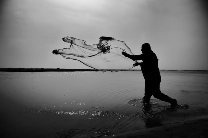 A person in shadow casting a fishing net