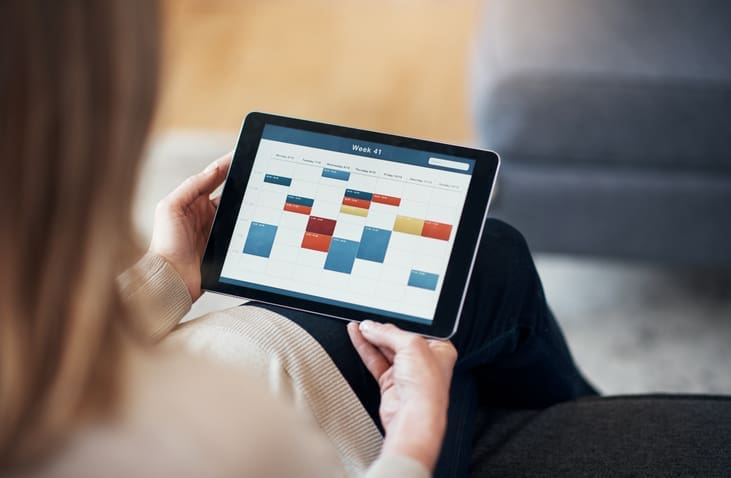 A person using a tablet with a scheduling tool displayed